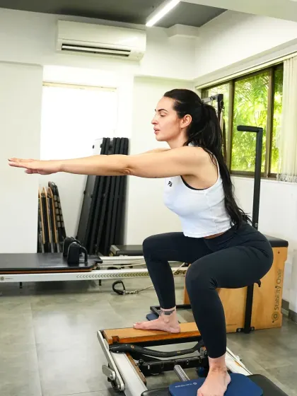 A client demonstrates a deep squat on the reformer. Pilates is a mindful dialogue between body and mind, where every stretch and movement is done with presence and alignment.
