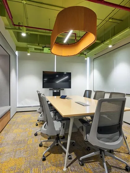 This meeting room features a window-seat for a more relaxed feel, a large whiteboard, and a unique pendant light. The green and yellow color scheme is energetic and positive.