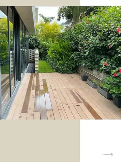 A sleek wooden patio extends along the villa's glass facade, providing a clean, modern outdoor living area. The space is softened by a thick hedge of flowering hibiscus, adding a touch of color and nature.