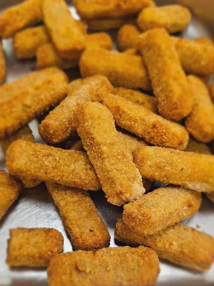 A tray of veg pizza fingers, ready to be packed into snack boxes or served hot at a party.