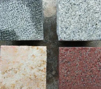 A sample of four different cobblestone colors I supply: two shades of grey granite, a yellow-toned stone, and a red granite.