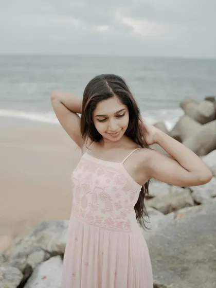 A portrait session at the beach, capturing a relaxed and natural moment. The soft ocean light and her candid pose make for a beautiful and serene lifestyle photograph.