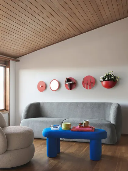 Our Aabhla collection reimagines the traditional Lipan Kaam craft of Kutch for modern interiors. This wall display features a composition of circular mirrors, shelves, and planters, adding a vibrant, culturally rich focal point to a contemporary living space.