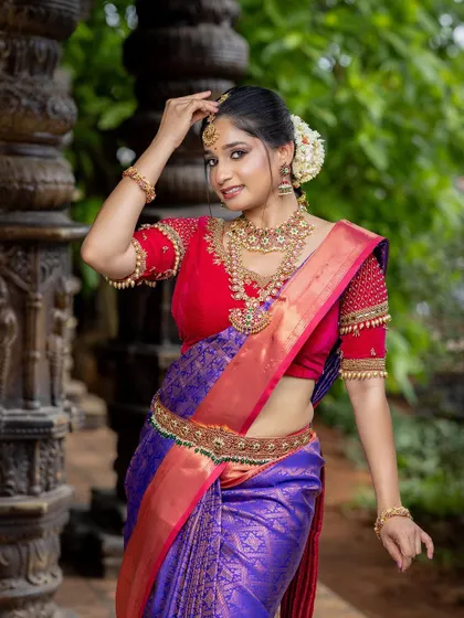 A close-up of the red and purple silk saree, focusing on the intricate jewelry and flawless makeup. This look is perfect inspiration for any bride-to-be.