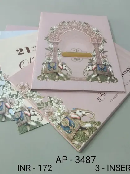 A blush pink invitation featuring two elephants under a floral arch. The design is sweet and traditional, with three inserts to accommodate all your event details.