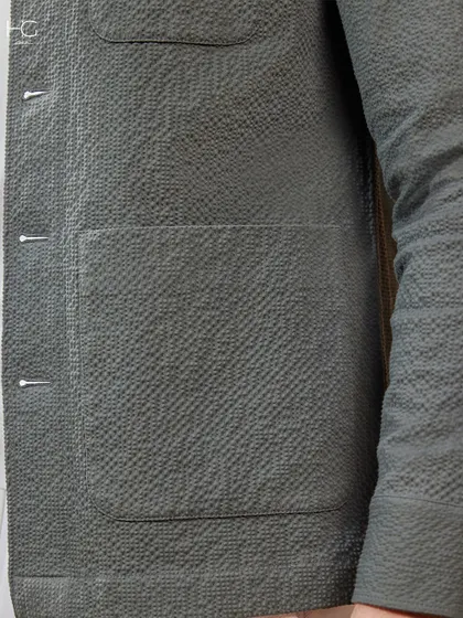 A detail shot of the textured fabric on the olive green shacket, highlighting the craftsmanship and quality that goes into every piece.