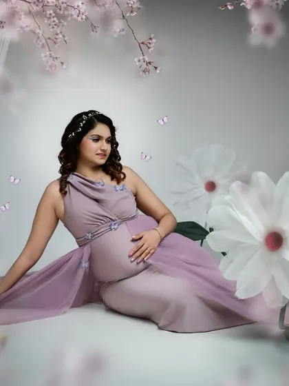 A fairytale moment. Surrounded by cherry blossoms and butterflies, this mother-to-be in a flowing lilac gown looks like she's stepped out of a dream.
