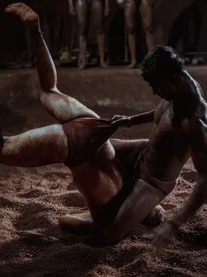 Action shots from inside the taleem, showing wrestlers locked in combat. The low lighting and shadows emphasize the raw power and technique of the grappling matches.