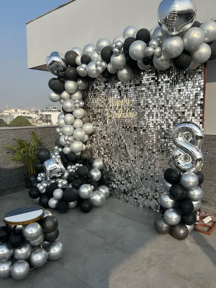 This stunning rooftop setup for a birthday featured a glamorous silver sequin wall, a black and silver balloon arch, and a comfortable, low-seating arrangement under a canopy of fairy lights. It was the perfect blend of chic and cozy for an evening celebration.