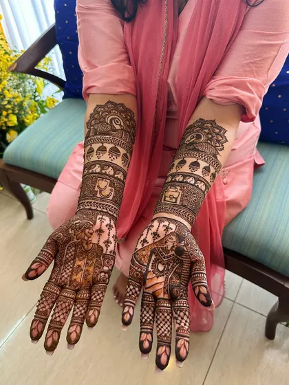Full-arm bridal mehndi featuring detailed portraits of the bride and groom. The design also includes elephants and peacocks, classic symbols of prosperity and beauty in Indian weddings.