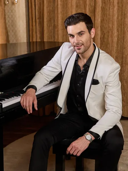 A relaxed moment in a sharp white tuxedo. The shawl lapel with black piping gives a modern edge to a timeless classic. This is the perfect attire for a sophisticated cocktail party or a black-tie wedding.
