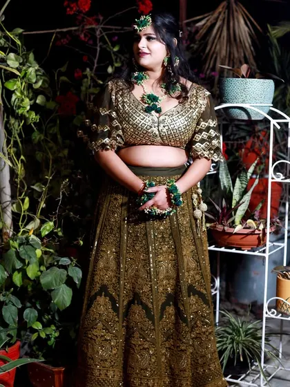 A beautiful outdoor portrait of the bride on her Mehndi day. The natural greenery complements her olive green lehenga and floral jewelry perfectly.