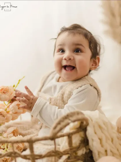 A close-up shot of a happy baby in a basket, interacting with some flowers. We use simple props to bring out their natural curiosity.