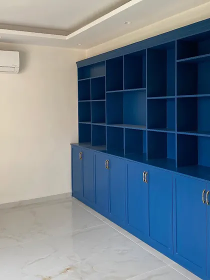 A bold and beautiful custom-built bookshelf and storage unit, painted in a vibrant royal blue, ready to become the centerpiece of a study or living room.