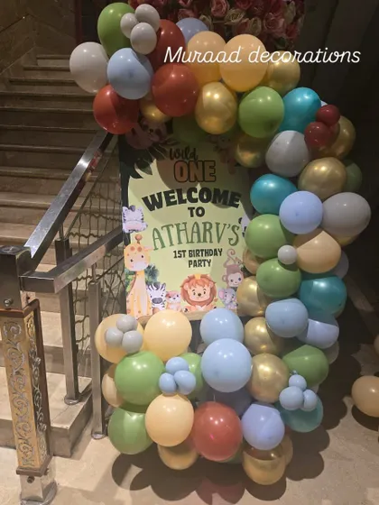 A welcome sign for a jungle-themed first birthday party. A custom poster greets guests at the entrance, surrounded by a colorful balloon garland that sets a fun and wild tone.