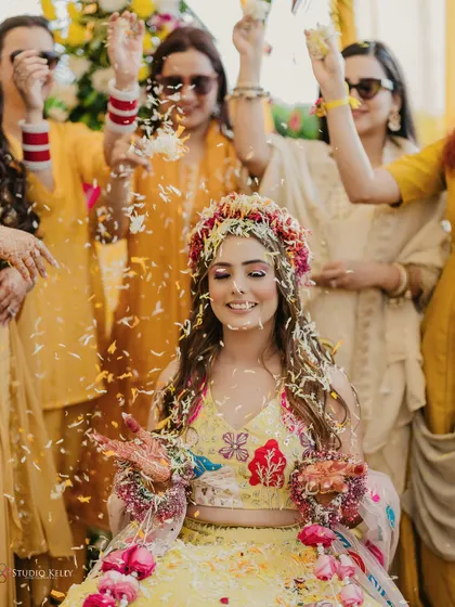 A beautiful shot of the bride being showered with flowers by her bridesmaids during her sunny Haldi ceremony.