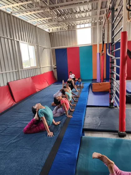 Flexibility is a cornerstone of gymnastics. Here, students are practicing their backbends on the mat, a key exercise for building strength and agility.