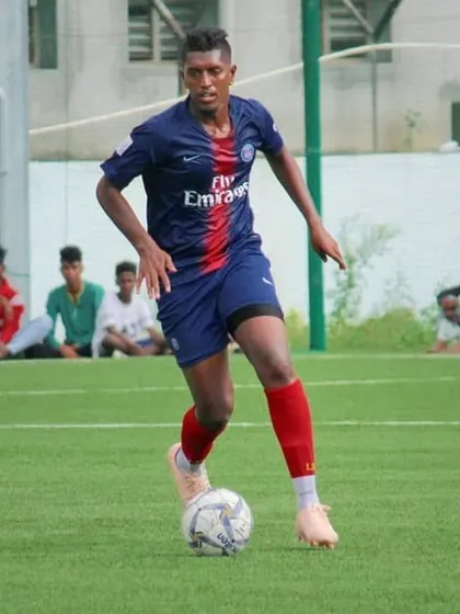 Stalin dribbling the ball in a match. He combines his playing career with coaching, bringing real-world experience to our kids.