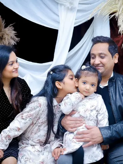 A big sister gives her baby sister a kiss on the cheek. A precious moment from their family studio session.