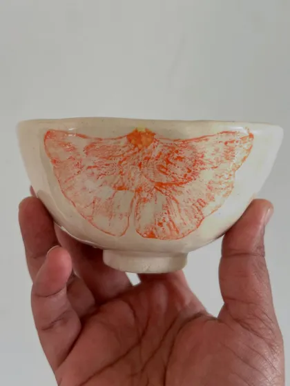 A small, wheel-thrown bowl featuring a moth design created with an underglaze transfer.