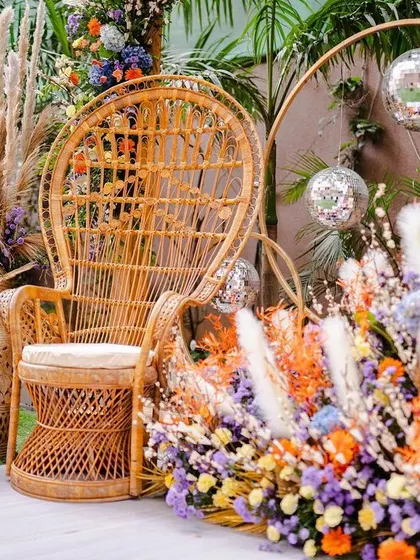 The bride's special seating for the Mehendi ceremony. A peacock wicker chair is surrounded by a riot of colorful flowers, creating a perfect throne for the bride-to-be.