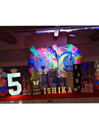 Our unicorn theme is pure magic. This setup for Ishika's birthday features pastel unicorn illustrations on pedestals, a rainbow balloon arch, and light-up letters for an enchanting party.