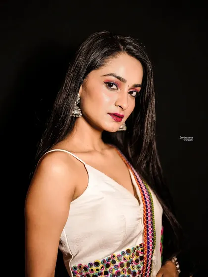A powerful studio portrait for Navratri. The model's direct gaze, combined with the traditional white lehenga and silver jewelry, creates a look of modern confidence.