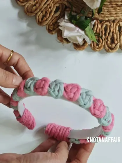 Holding the finished macrame rose flower hairband. This is a great example of a unique, handmade accessory that you won't find in stores.