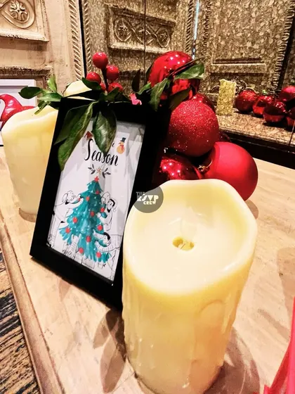 Simple and festive decor, with pillar candles, red berries, and a framed Christmas tree print.