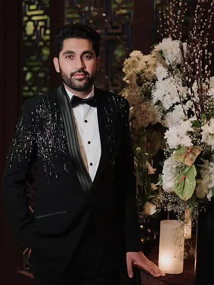 A dapper portrait of the groom in his embellished tuxedo, looking sharp and ready for a night of celebration.