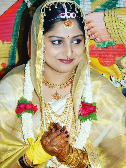 A candid shot of a bride in a beautiful cream and gold saree, her face veiled, during a wedding ceremony.
