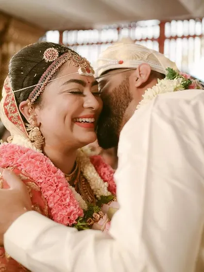 A candid, happy moment between the bride and groom, sharing a hug and a laugh right after a ritual.