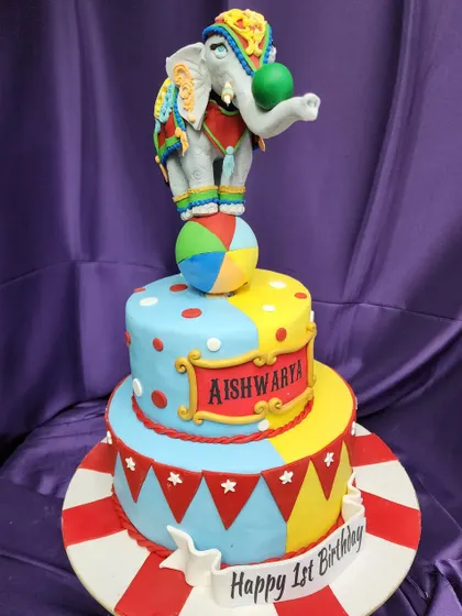 This circus elephant theme cake is a colorful and cheerful centerpiece for a first birthday. The detailed, handcrafted elephant balancing on a ball is the star of the show.