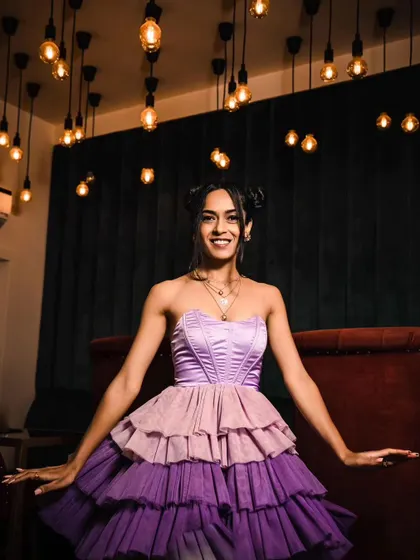 A happy, seated pose showing the full dress under ambient lighting.