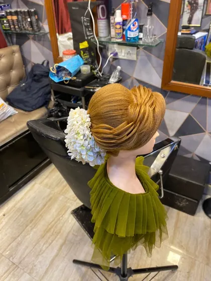 A modern, sculptural updo with clean lines and a large floral accessory. This style shows how to blend sharp, defined sections with soft elements for a high-fashion look.