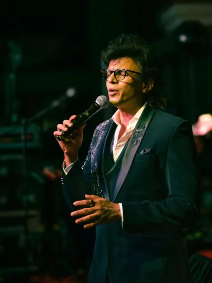 A close-up of Abhijeet Sawant, showing the detailed embroidery on the lapels of his tuxedo jacket as he performs.