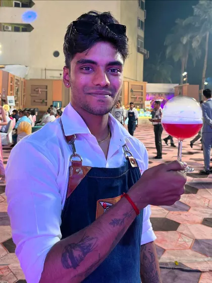 A guest's perspective of our bartender presenting the 'Bubble Pop' cocktail in a crowded event space.
