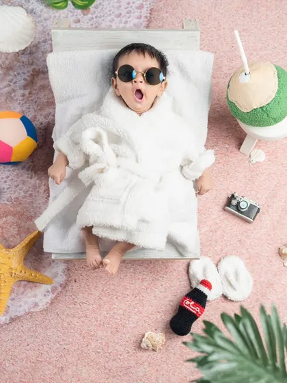 A newborn enjoying a spa day at the beach. The tiny bathrobe and sunglasses are just too cute.