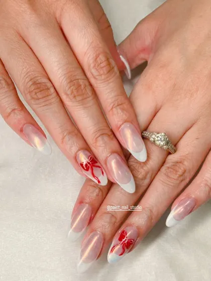 A simpler, yet equally beautiful Christmas look. This features a classic white French manicure on a shimmery base, with two accent nails padrões with hand-painted red bows.