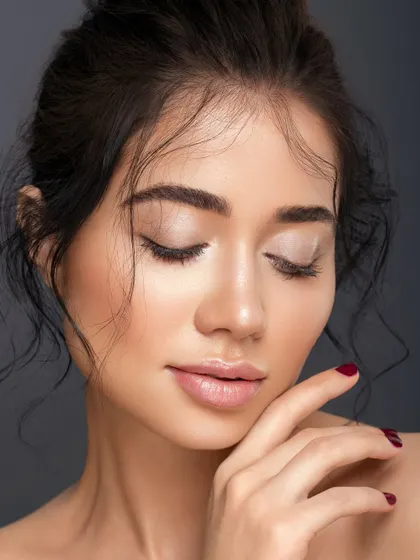 A serene portrait with eyes closed, emphasizing the soft, neutral eyeshadow and the perfectly groomed brows. The pose is calm and contemplative, highlighting the elegance of a minimalist look.