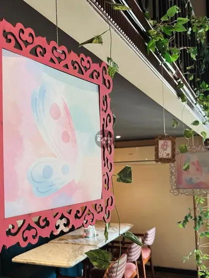 Large, ornate frames with watercolor butterfly art were hung from the ceiling, adding a touch of elegance and whimsy to the fairy theme.