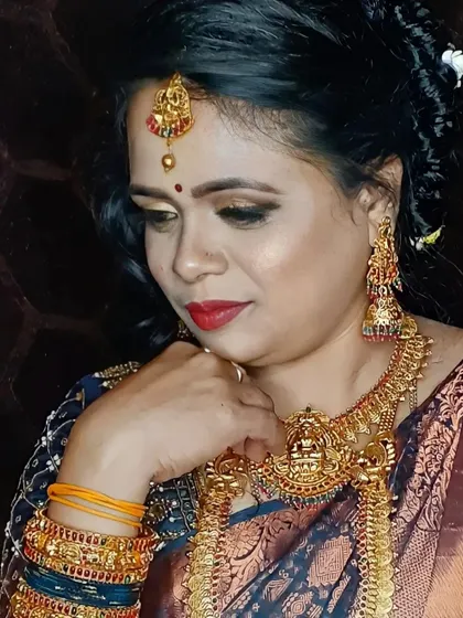 A close-up of another traditional bridal look. The eye makeup is a soft, smokey brown, paired with a classic red lip. The temple jewellery, including the maang tikka and jhumkas, completes this timeless style.
