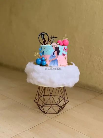 A whimsical "Mom to be" cake with a dreamy cloud-like base. The pink and blue colors with butterfly accents make it perfect for a baby shower.