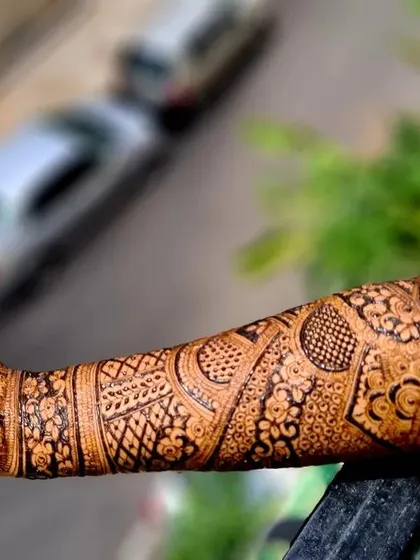 A stunning outdoor shot of a bride's full-arm henna, showcasing the intricate patterns against a natural background.