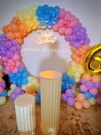 A rainbow unicorn theme for a 6th birthday. This features a circular balloon arch, a 'Happy Birthday' neon sign, a large number '6' foil balloon, and plinths for the cake.