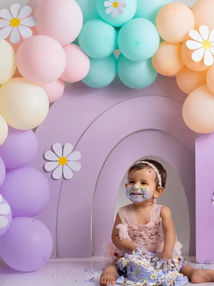 Sitting proudly amidst the beautiful pastel setup after a successful cake smash. This shot captures the calm after the storm, with a very satisfied-looking one-year-old.