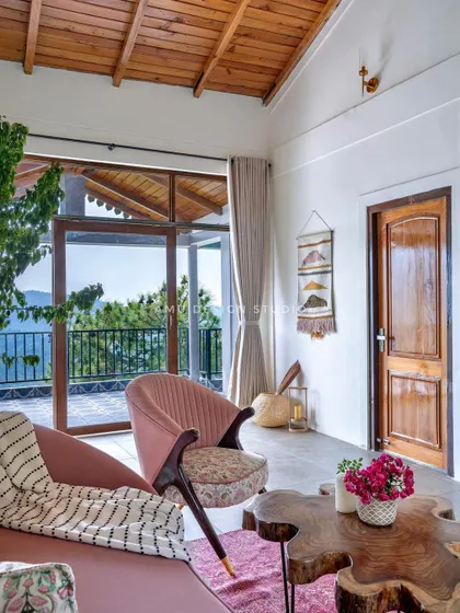 A corner of the lounge in our Mukteshwar project, where a custom pink armchair with floral upholstery sits beside a large window, offering a perfect spot to enjoy the valley views.