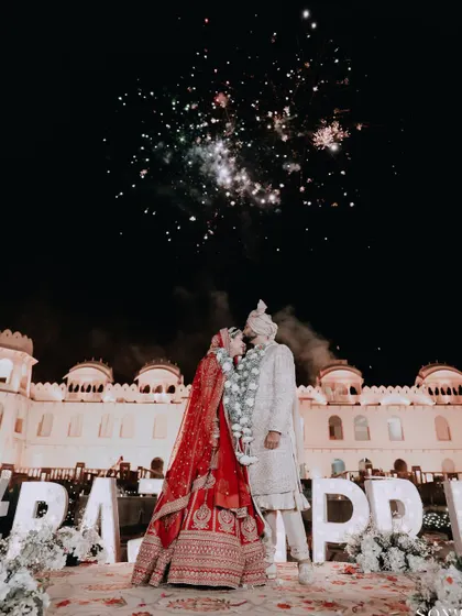 A spectacular shot of the couple kissing under a sky full of fireworks, a perfect fairytale ending to their wedding day.