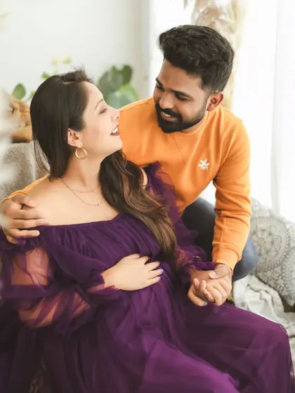 A sweet and candid photo of an expecting couple. Their shared smiles and gentle touch show the happy and relaxed connection they have as they wait for their baby.
