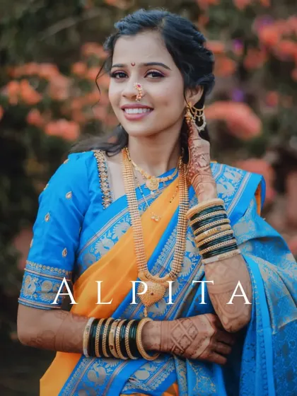 A lovely portrait of the bride, Alpita, in her vibrant blue and yellow saree, with her name elegantly watermarked.